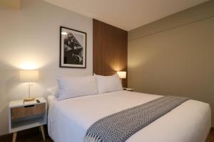 een hotelkamer met een wit bed en een nachtkastje bij Monochromatic 2BR in Miraflores in Lima