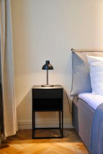 a nightstand with a lamp on it next to a bed at Aparthotel Mageløs 12 in Odense