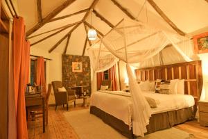 a bedroom with a canopy bed and a desk at Gorilla Safari Lodge in Rubuguli