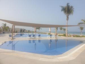une grande piscine avec des chaises et des palmiers dans l'établissement Peace in Sifah -Sea view, à As Sīfah