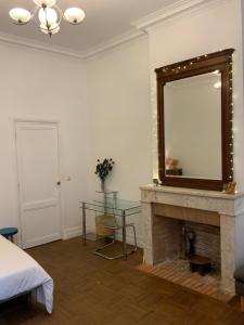 a bedroom with a fireplace with a mirror and a table at Grand studio style bordelais dans le triangle d'or in Bordeaux