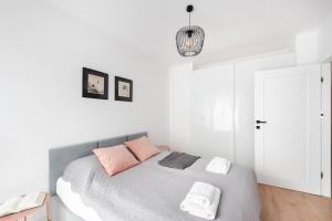 a white bedroom with a bed with pink pillows at Spacious and modern Apartment Lwowska, close to Kazimierz in Kraków