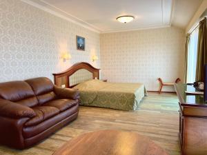 a bedroom with a bed and a leather couch at Aqua View SPA Boutique Hotel in Golden Sands