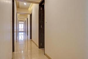 a hallway with white walls and tile floors and a mirror at Collection O Hotel Royce Studios Near Pune Airport in Pune