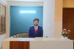 a man in a suit and tie standing behind a desk at Hotel Ginger Palace - Corporate stay business hotel in Noida