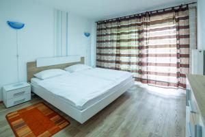 una camera con un letto bianco e una grande finestra di Apartments Silva a Ljutomer