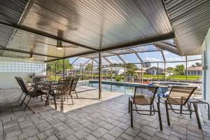 un patio con mesa, sillas y piscina en Direct Sailboat Access & Southern Exposure Heated Pool - Villa Coconut Hideaway - Roelens, en Cabo Coral