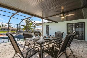comedor con mesa y sillas en el patio en Direct Sailboat Access & Southern Exposure Heated Pool - Villa Coconut Hideaway - Roelens, en Cabo Coral