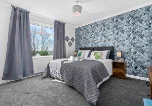 a bedroom with a bed with a blue and white wallpaper at Coats Street Apartment by Klass Living Coatbridge in Coatbridge