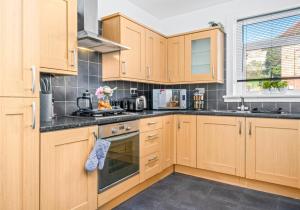 una cocina con armarios de madera y encimeras negras en Coats Street Apartment by Klass Living Coatbridge en Coatbridge