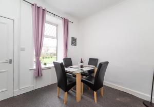 ein Esszimmer mit einem Tisch, Stühlen und einem Fenster in der Unterkunft Albion Apartment by Klass Living Coatbridge in Coatbridge