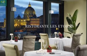 un restaurante con mesas y sillas y vistas a la capital en Atlante Star Hotel en Roma