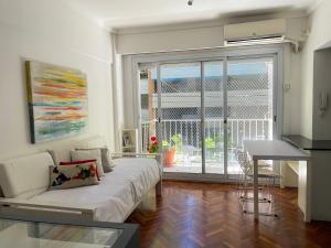 ein Wohnzimmer mit einem Sofa und einem großen Fenster in der Unterkunft Studio Palermo Hermoso Con Balcon in Buenos Aires