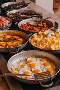 stół z patelniami wypełnionymi jajami i żywnością w obiekcie Brown Beach Chalkida, a member of Brown Hotels w Chalkidzie