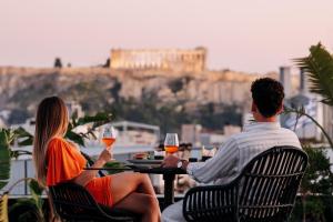 a man and woman sitting at a table with wine glasses at Skylark, Aluma Hotels & Resorts in Athens