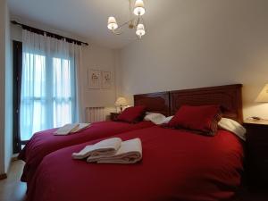 a bedroom with a red bed with towels on it at Inmocyma Cerler-Prados de Velarta C2 8 -vistas panorámicas in Cerler
