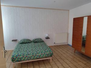 a bedroom with a bed with a green comforter at Maison pour 6 personnes in Lassicourt