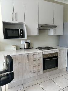 米德蘭的住宿－Gallagher Midrand BnB，厨房配有白色橱柜和炉灶烤箱。