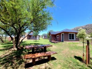 a picnic table in the grass in front of a house at Cabañas la Delfina in Potrero de los Funes