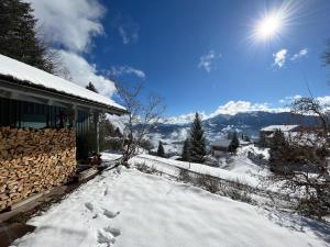 a snow covered yard next to a house with the sun at Bregenzerwald Ferienhaus in Egg +17 photos
