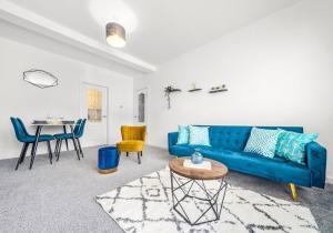 - un salon avec un canapé bleu et une table dans l'établissement Back'o'Barns Apartment by Klass Living Hamilton, à Hamilton