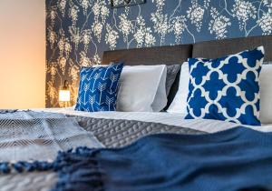 Schlafzimmer mit einem Bett mit blauen und weißen Kissen in der Unterkunft Back'o'Barns Apartment by Klass Living Hamilton in Hamilton