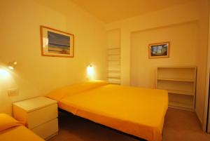 Dormitorio amarillo con 2 camas y sofá en Appartamenti family & MTB, en Finale Ligure