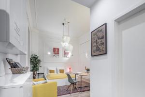 a white living room with yellow chairs and a table at Extra Central Modern Studio in Budapest