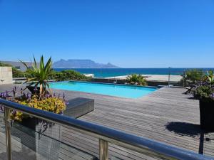 a deck with a swimming pool and the ocean at Infinity 602 in Bloubergstrand