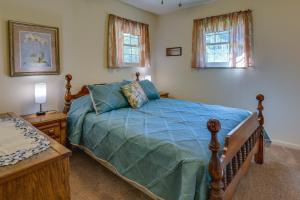 a bedroom with a bed with a blue comforter and two windows at Vintage Chipley Getaway on Large Private Property in Chipley