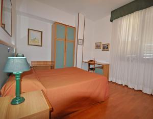 una camera con letto e tavolo con lampada di Hotel Elisa a Porto Torres