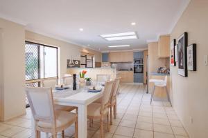 a kitchen and dining room with a white table and chairs at Decorated with love 4BD Family House with Pool in Brisbane