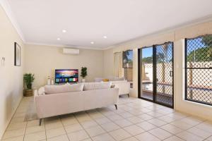 a living room with two white couches and a tv at Decorated with love 4BD Family House with Pool in Brisbane