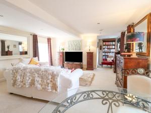 a living room with a white couch and a tv at Dovecote Cottage in Ashbourne