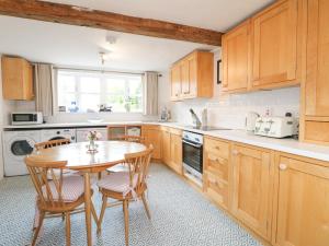 uma cozinha com armários de madeira e uma mesa e cadeiras em Dovecote Cottage em Ashbourne
