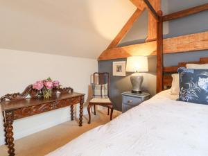 um quarto com uma cama e uma mesa com flores em Dovecote Cottage em Ashbourne
