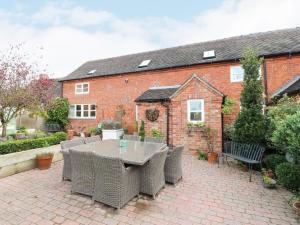 a patio with a table and chairs in front of a brick house at Dovecote Cottage in Ashbourne