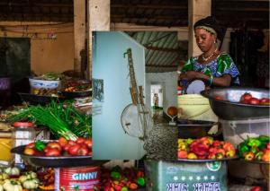 a woman standing in a kitchen with fruits and vegetables at Seaview Superior Room in Cape Point Bakau in Bakau