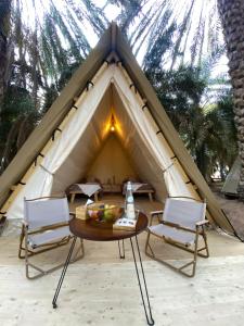 a table and chairs in front of a tent at Husaak Glamping in AlUla