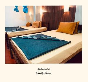 two beds in a hotel room with blue decorations at Madhusha Rest in Maskeliya