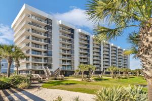 a large white apartment building on the beach with palm trees at Mainsail 131 - Beachfront 2BR with Free Seasonal Beach Service in Destin