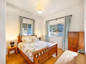 1 dormitorio con 1 cama y 2 ventanas en Family friendly cozy 4BR house at Annerley, en Brisbane