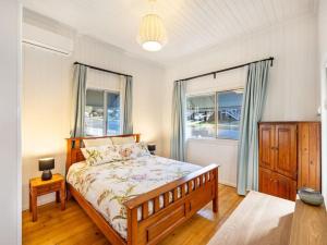 a bedroom with a bed and two windows at Family friendly cozy 4BR house at Annerley in Brisbane