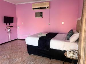 a bedroom with a pink wall and a bed at Flamingo B&B in Richards Bay