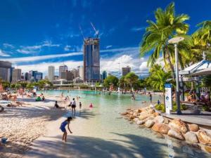 un grupo de personas jugando en el agua en una playa en Riverview 2BR delicate Apt, 1min to train station en Brisbane