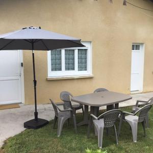 a table and chairs with an umbrella in the grass at Logement avec parking max 7 personnes in Eauze