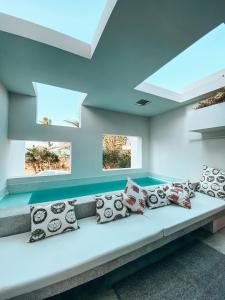a room with a couch with pillows and windows at Auka Boipeba in Ilha de Boipeba