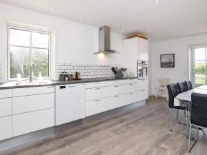 a kitchen with white cabinets and a table with chairs at Holiday home Læsø IV in Læsø