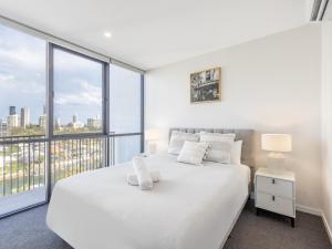 a bedroom with a white bed with a large window at Riverside 2BR delicate apt in Gold Coast