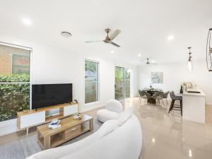 a white living room with a tv and a couch at 4BR Cozy house 5mins to beach in Gold Coast